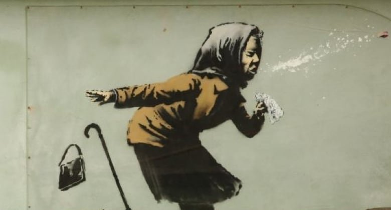 A person photographs a mural created by British artist Banksy entitled "Aachoo!!" showing a woman wearing a headscarf sneezing and dropping their handbag and cane is seen on the side of a house in Bristol, southwest England.