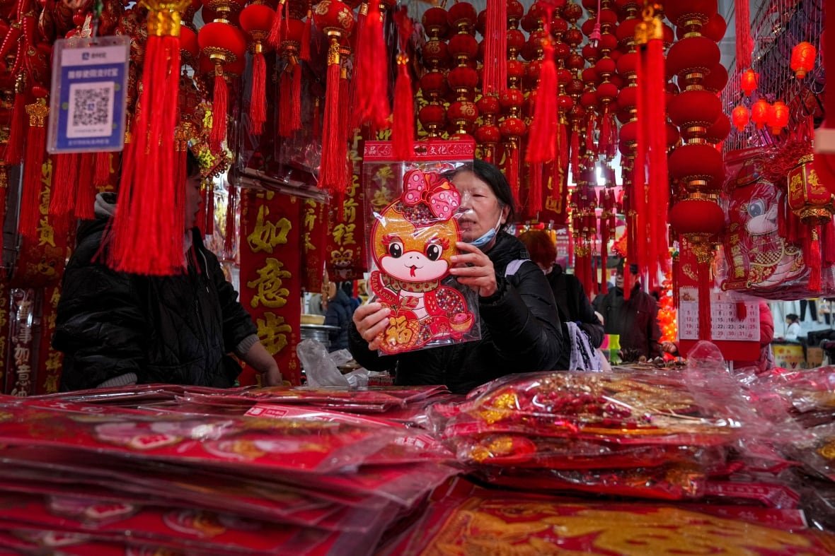 china-lunar-new-year A woman holds a cute snake decoration in a decoration store.