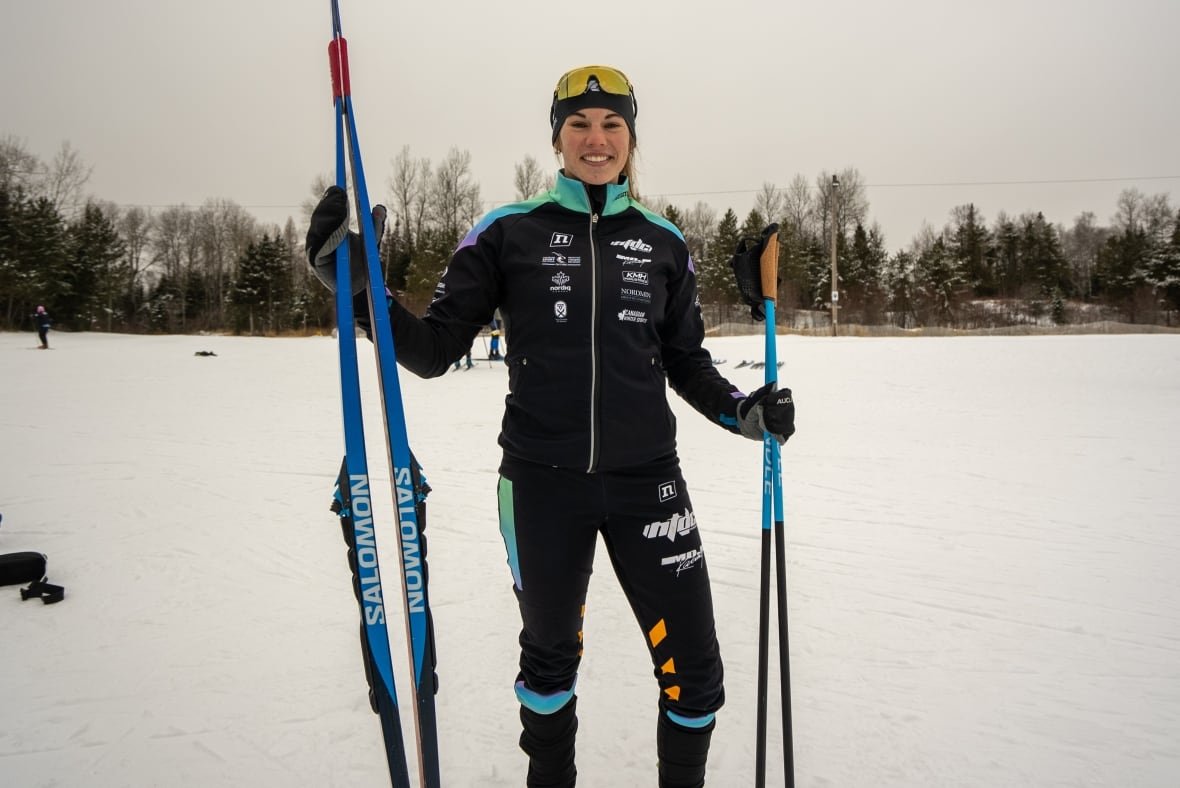 clara-hegan A woman holding cross-country skies smiles for a photo.