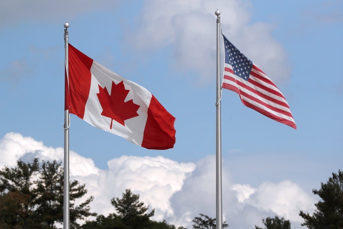 health-coronavirus-usa-canada The American and Canadian flags fly side by side in front of a blue sky.