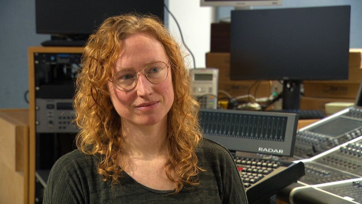 kelly-mcmichael A woman with curly red hair and glasses.