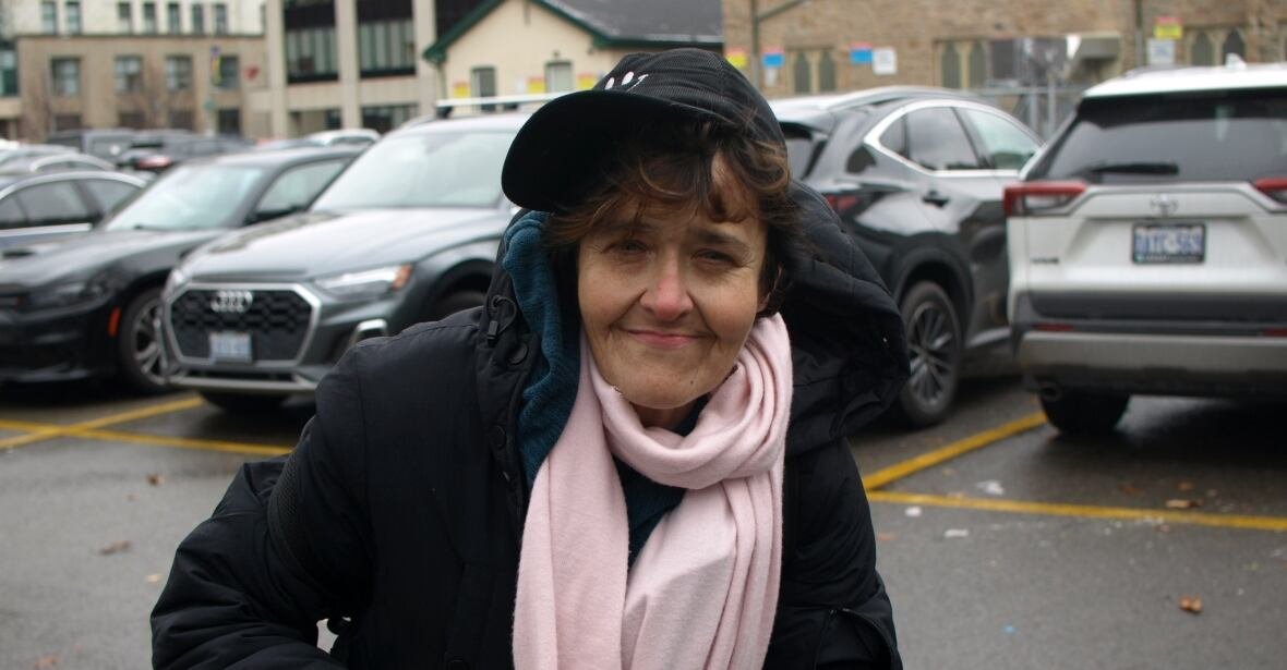 kimmy-taylor A person with a baseball cap and scarf smiles and squints