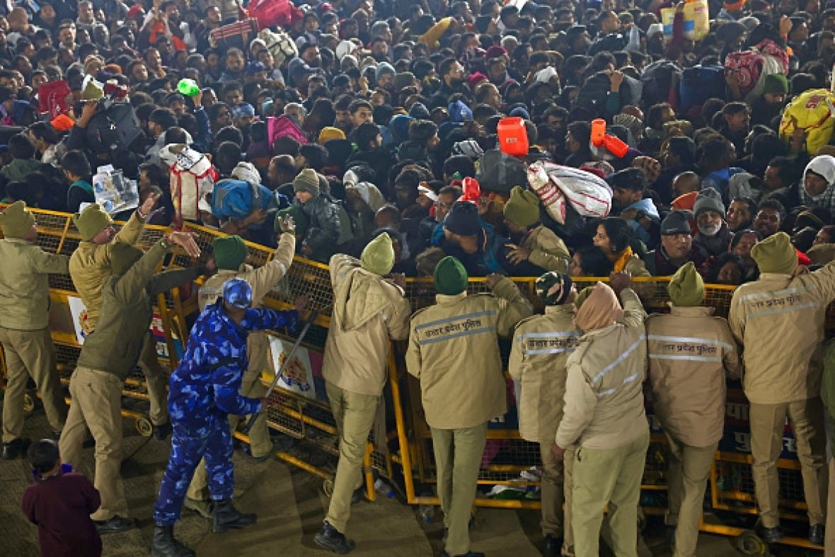 kumbh-mela-festival-1 A crowd pushes against a chain link fence. On the other side, security guards attempt to push back the crowd.