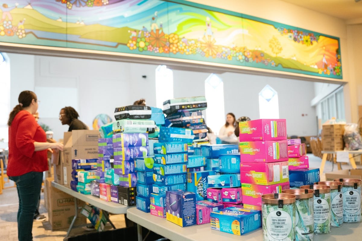 menstrual-products-on-a-table People in the background, foreground has menstrual products on the table.