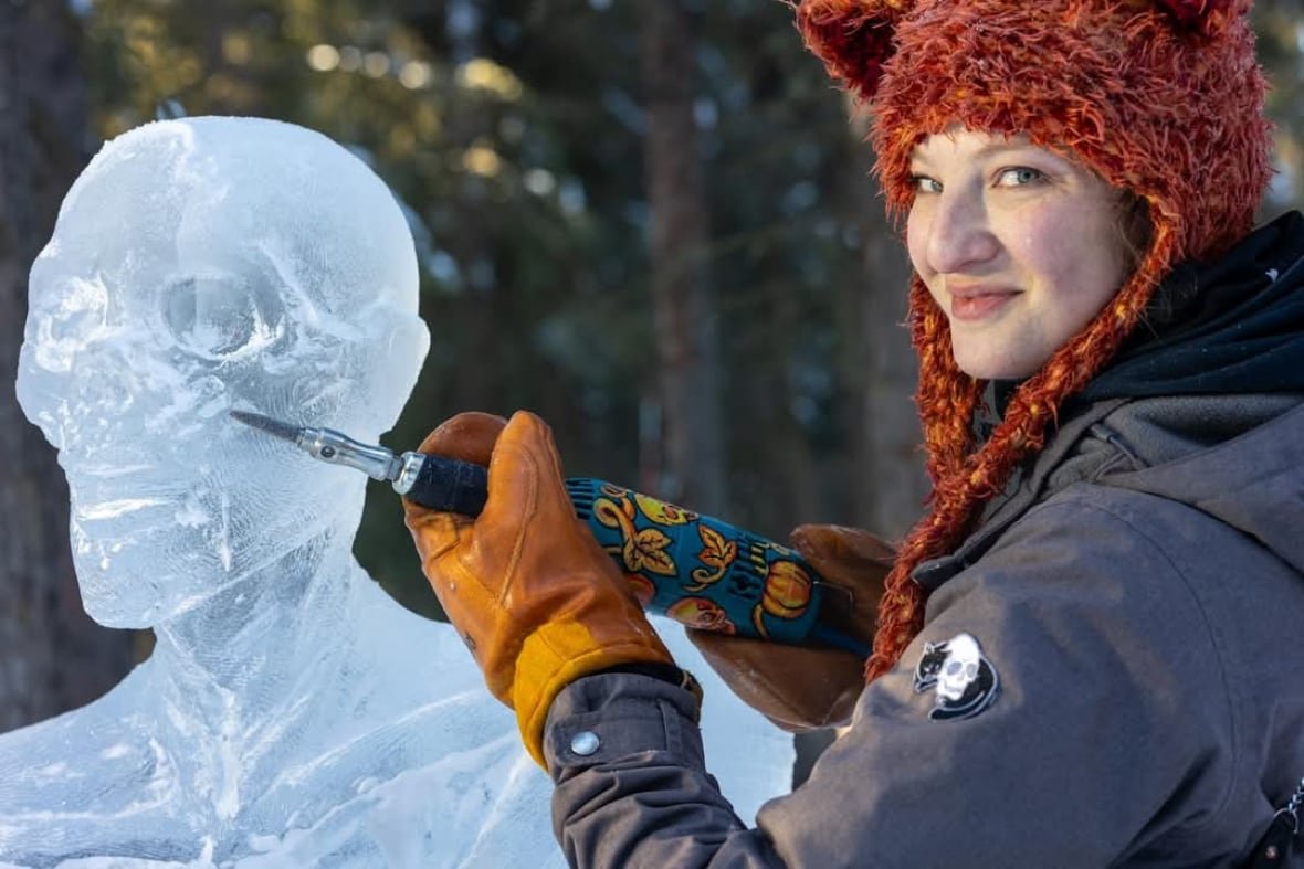 sarah-blostein-ice-carving A woman dressed in winter attire holding a chisel while carving a skull on ice.