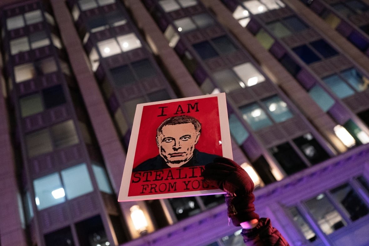 usa-trump-protests A person holds up a print saying "I am stealing from you" with a man's face.