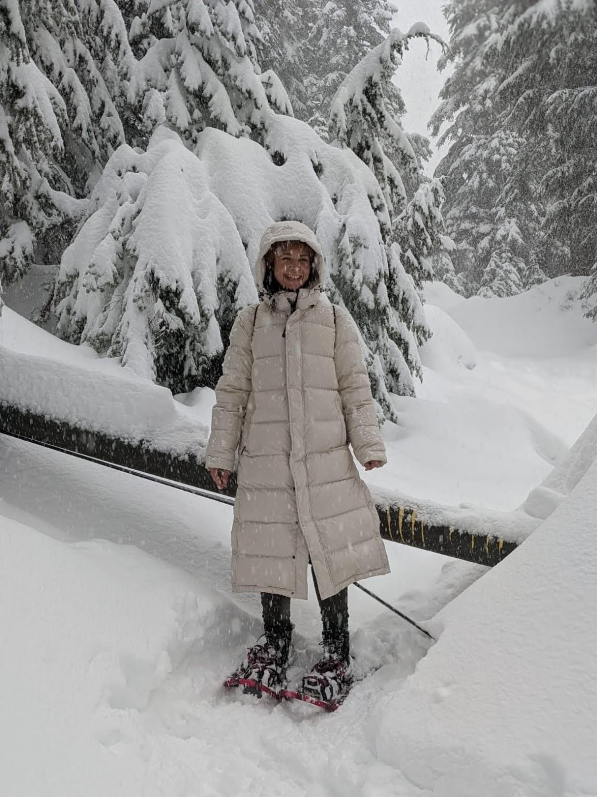 A woman snowshoeing on a trail in a snowy forest.