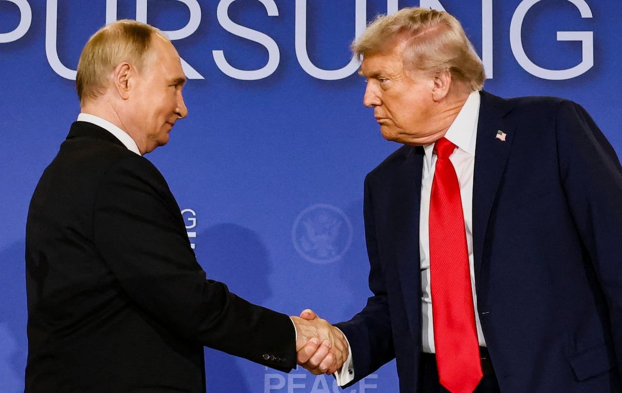default-221 Two men in suits shake hands. One is smiling slightly.